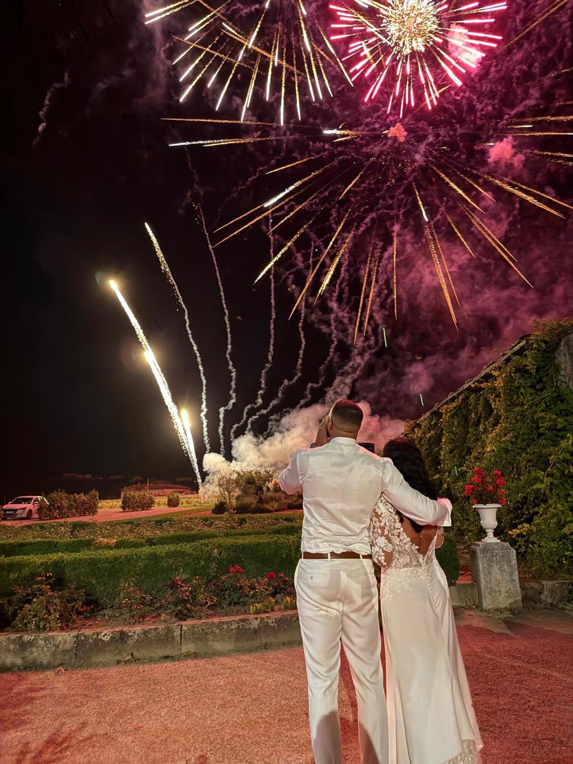 Mariés admirant un feu d'artifice rose et doré dans un jardin de château — Éclats Étincelants