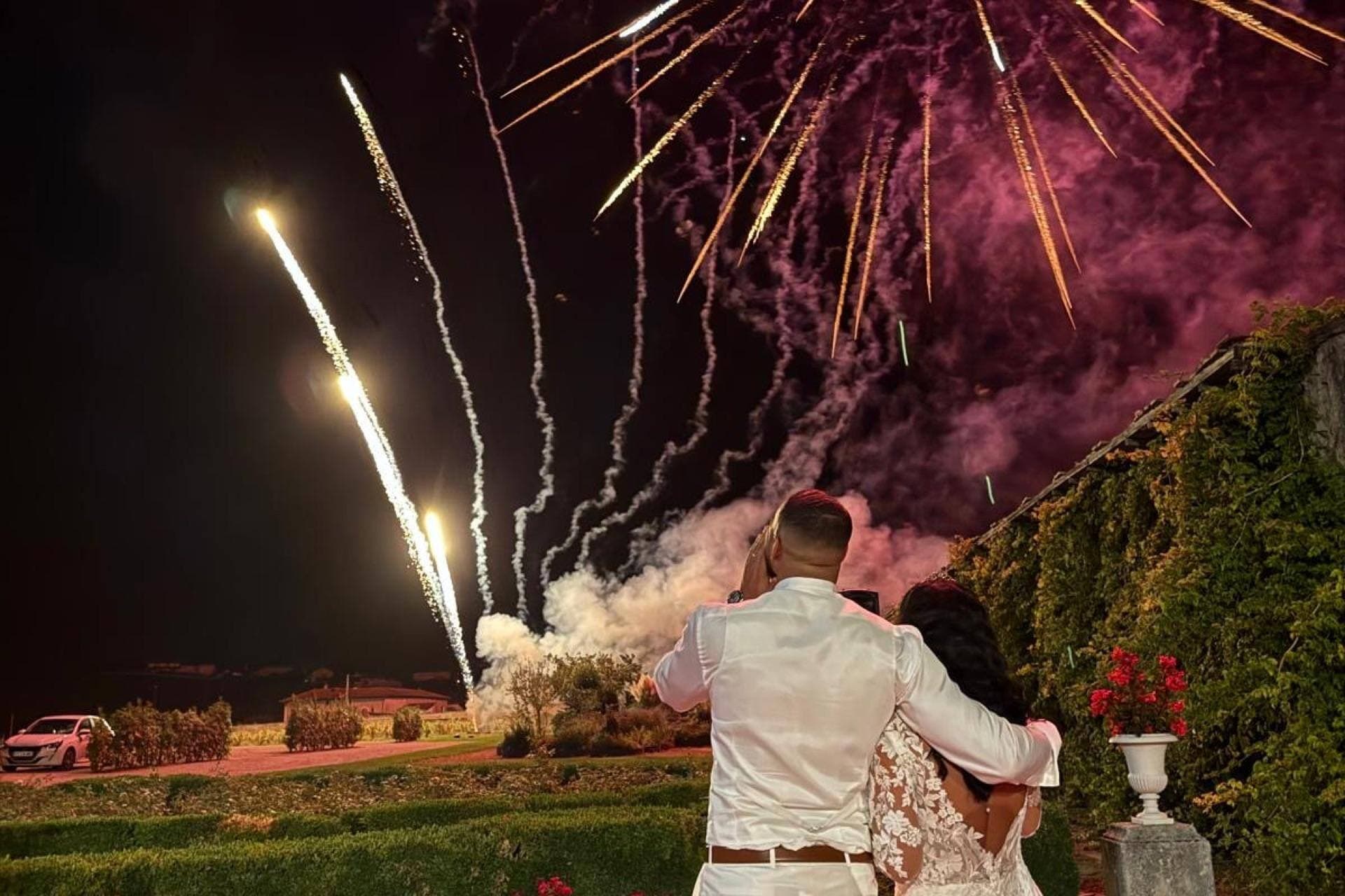 Mariés admirant un feu d'artifice rose et doré dans un jardin de château — Éclats Étincelants